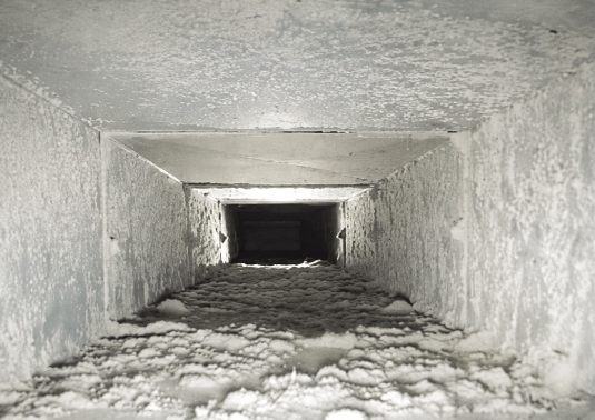 Dirty air duct with heavy dust buildup before professional cleaning